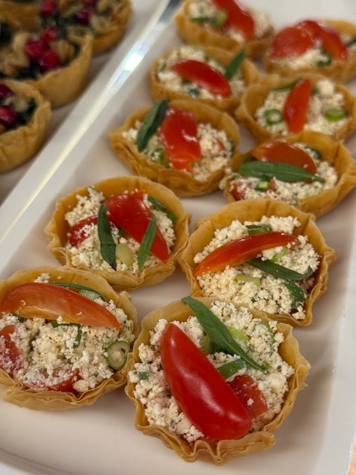 Delicious tomato and cheese tartlets garnished with herbs, perfect for appetizers.